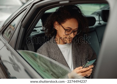 Pretty woman entrepreneur use phone during traveling to office in back seat of luxury car Royalty-Free Stock Photo #2274494237