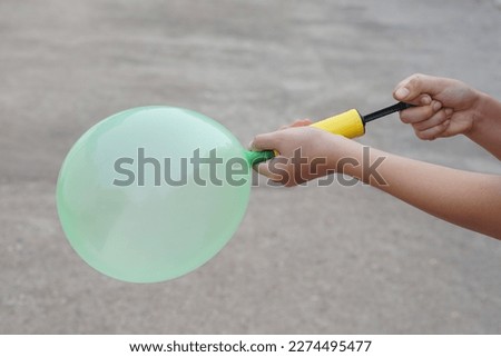 Blowing green balloon by hand air pump, inflates  air to balloon Concept, children play, toy and equipment to play fun games or prepare party.                          Royalty-Free Stock Photo #2274495477