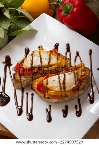 Crostini rustici Toasted ciabatta bread topped with roasted peppers, goats cheese and balsamic glaze Royalty-Free Stock Photo #2274507529
