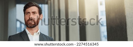 Focused european businessman with coffee and phone near office building during break looking away