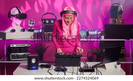 Asian performer mixing and mastering techno sound using professional turntables, enjoying performing music during night party in club. Dj artist doing performance with audio equipment