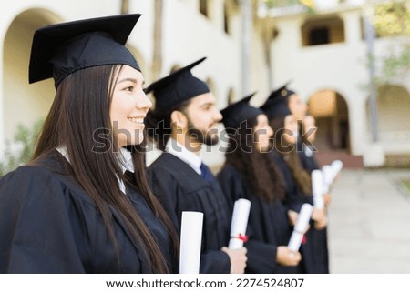 College graduates smiling wearing black graduation gowns looking happy while receiving their university diplomas Royalty-Free Stock Photo #2274524807