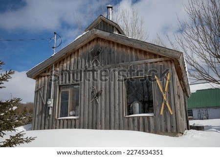 Sugar shack, old traditional barn in Quebec, Canada, surrounded by snow with vintage ski decoration Royalty-Free Stock Photo #2274534351