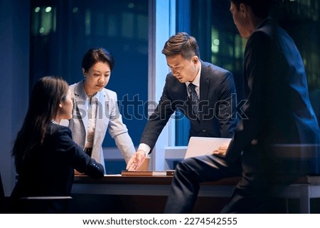 team of asian business people meeting in office reviewing performance and formulating strategy Royalty-Free Stock Photo #2274542555