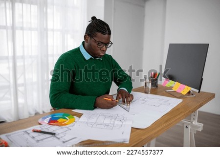 Black Male Designer Working Drawing With Pencil And Ruler Creating House Plan Sitting Near Big Computer In Modern Office. Design And Architecture, Successful Career Concept