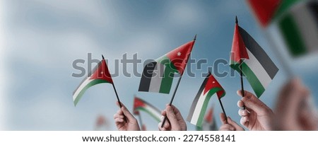 A group of people holding small flags of the Jordan in their hands. Royalty-Free Stock Photo #2274558141