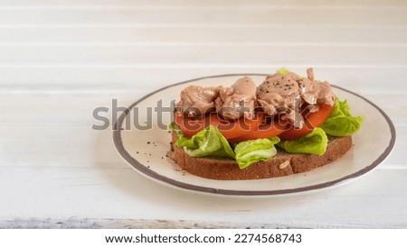 Cod liver sandwich on ceramic plate.