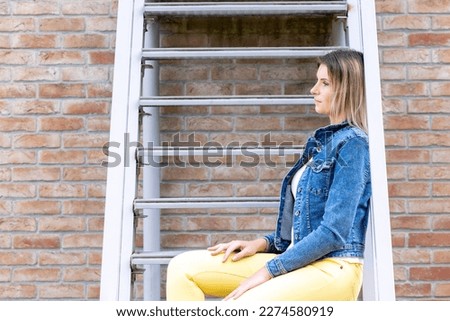 smiling young woman sits on stairs. urban scene. High quality photo