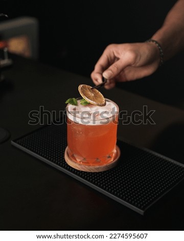Barman making a tasty and sweet old fashioned summer cocktail with orange juice on the bar counter and black background Royalty-Free Stock Photo #2274595607