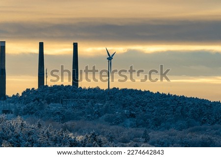 Wind power turbine looking out over a winter forest.