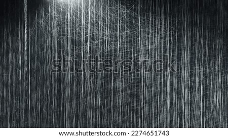 Raindrops illuminated by a street lamp during a downpour on a dark background. Atmospheric natural texture Royalty-Free Stock Photo #2274651743