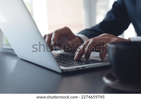 Businessman online working on laptop computer, surfing the internet, networking at modern office, closeup. Business man hand typing ob laptop computer keyboard on office desk Royalty-Free Stock Photo #2274659745