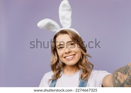 Close up young funny woman wearing casual clothes bunny rabbit ears doing selfie shot pov on mobile cell phone isolated on plain pastel light purple background studio. Lifestyle Happy Easter concept
