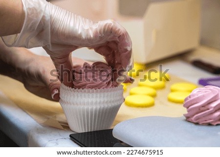 a woman confectioner puts a fruit marshmallow in a paper wrapper. hands close up. home bakery concept.