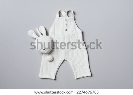 White romper and soft bunny toy on grey background. Set of baby stuff and accessories for newborn on grey background. Baby shower or baby care concept. Fashion newborn. Flat lay, top view. Royalty-Free Stock Photo #2274696785