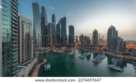 Dubai marina tallest skyscrapers and yachts in harbor aerial night to day transition  before sunrise. View at apartment buildings, hotels and office blocks, modern residential development of UAE