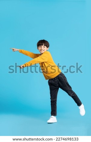 full body image of asian boy posing on blue background Royalty-Free Stock Photo #2274698133