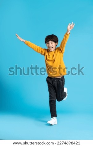 full body image of asian boy posing on blue background Royalty-Free Stock Photo #2274698421