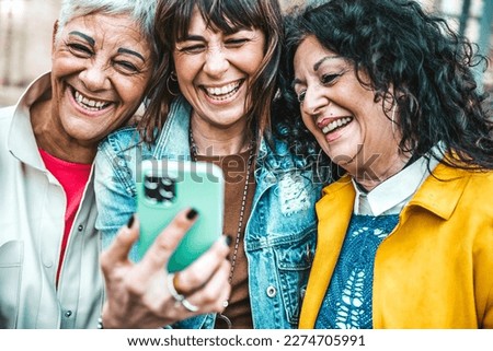 Group of senior female using smart mobile phone device outside - Three mature women having fun watching cellphone together - Generation x concept with older people addicted to social media  Royalty-Free Stock Photo #2274705991