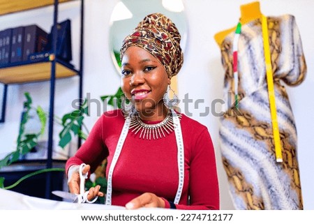 latin hispanic woman with fashionable turban over head and red dress working in clothess making office