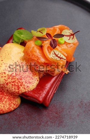 Colorful red crepes or blini with salmon and hollandaise sauce, decorated with micro greens on black plate. Gourmet snack. Fine dining. Close up view Royalty-Free Stock Photo #2274718939