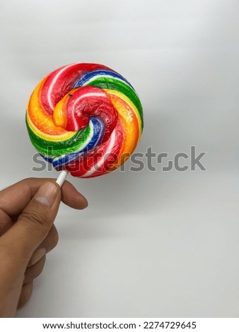 The left hand holding the lollipop stick rainbow color isolated on white background.