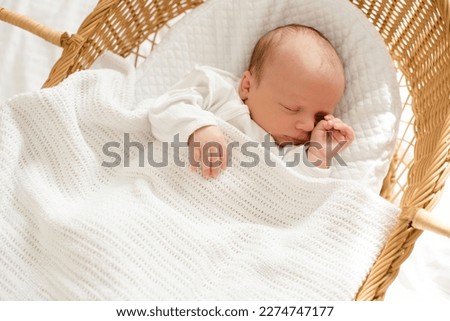 Little baby infant sleeping in straw crib wearing white pajamas at home top view. Childhood.  Royalty-Free Stock Photo #2274747177