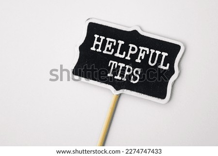 Helpful Tips - text on a small chalkboard on a neutral background. Top view. Business, tips and tricks concept
