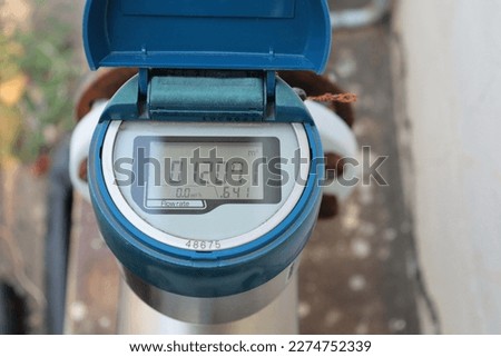 Blue digital water meter. Closeup of old and dirty electronic tap water flow meter outdoor with digital display and selective focus. Royalty-Free Stock Photo #2274752339