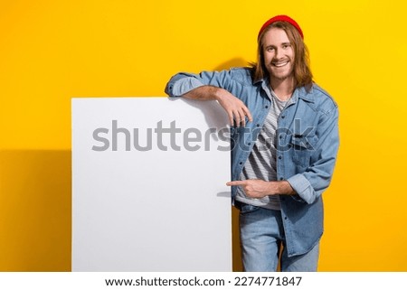 Portrait of good mood cool man with bob haircut wear denim jacket directing at offer empty space isolated on yellow color background