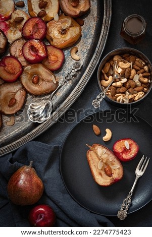 Baked apples, pears and plums with almonds, nuts and honey. Vintage tableware. Delicious and healthy dessert. Top view.  Low key photography. 