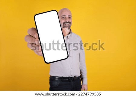 Smartphone advertisement, man holding showing recommending smartphone advertisement. New mobile app concept idea. Web site, online shopping. White blank screen mock up, yellow background, copy space.