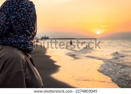 Side view Woman standing on beach alone on sunset looking at seascape landscape. Sunset light, golden hour. Nature and journey concept