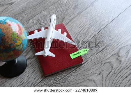 Selective focus image of toy plane, world globe and passport with text TRAVEL TIPS. Travel and transportation concept
