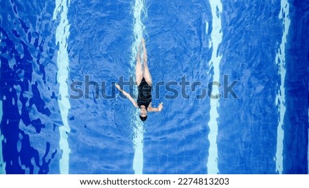 Aerial shot of a sporty girl who enjoys swimming alone in a large swimming pool