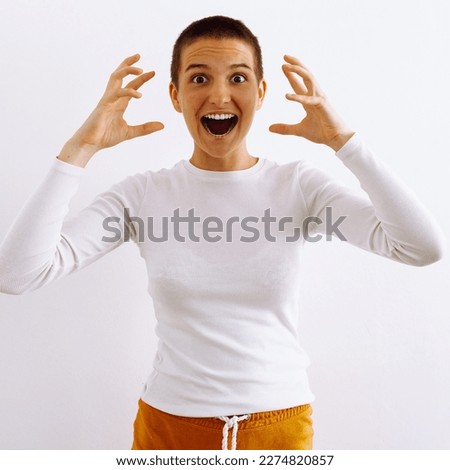 Portrait of young teenage girl, with short hair, in white golf, place for your logo or advertising, screaming in rage, raising hands to head, on white background