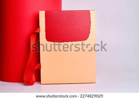Colored small gift box on a white and red background. Postal services, delivery. Mock-up packaging. Gift box, gift. Box close-up. Empty packaging, empty space