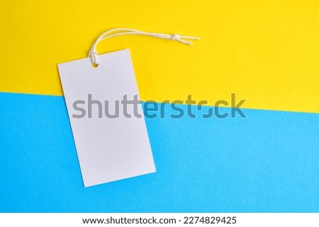 Empty tags eco white matte labels on a yellow-blue background. Eco friendly label concept. Layout. Space for text. Mockup