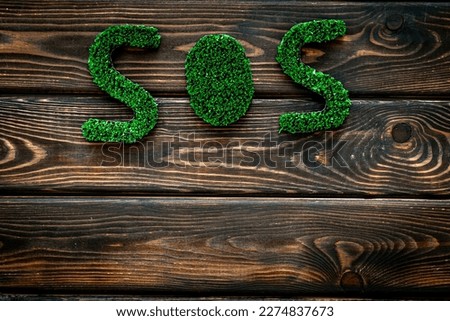 Word SOS made of green grass. Save the Earth planet ecology concept