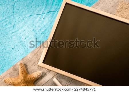 Photo frame without inscription seen from above on a wooden pavement above a pool with a starfish. Atmosphere vacations in summer.	