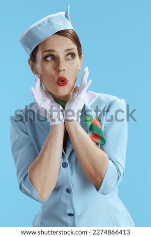 surprised modern flight attendant woman isolated on blue background in blue uniform.