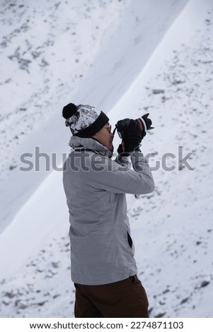 photographer taking pictures in the snow portrait of photographer taking pictures with digital camera outdoor
