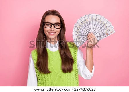Photo of cheerful young positive satisfied business lady wear stylish glasses enjoy her profit company hold money isolated on pink color background