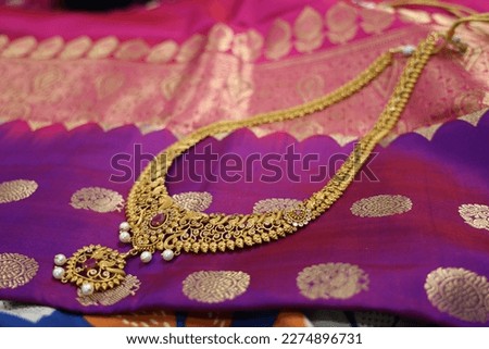 close up of antique stone  studded  gold jewelry necklace on a lovely purple silk fabric