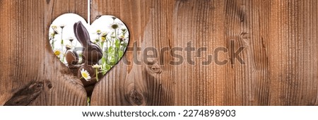 Easter chocolate bunny rabbit with daisies behind wooden planks panoramic background with a heart