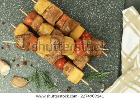 Fried meat and vegetables on wooden skewers. Meat cooked in a pan. View from above. Shish kebabs - grilled meat and vegetables