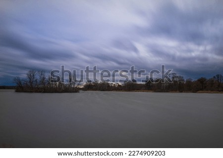 Bird island in the middle of the pond. Time lapse photography. Beautiful clouds blurred by photographic technique - .