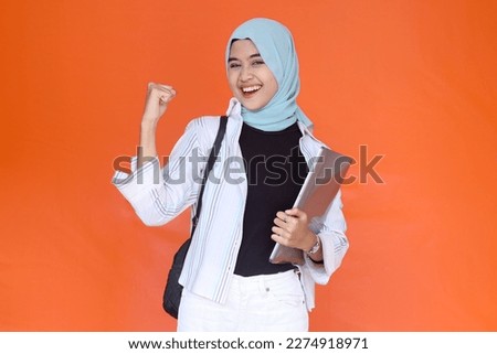 Asian muslim college student excited with her success good job while holding a laptop