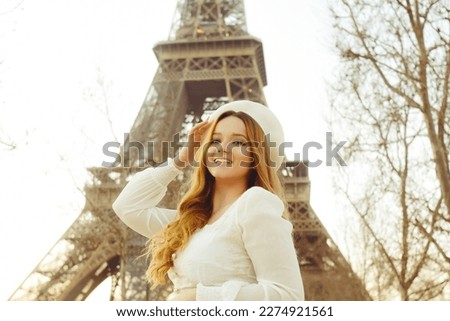 An incredibly beautiful girl in a long white dress and a beret against the background of the Eiffel Tower. Fashion in Paris, travel and weddings. Romance in the city of love, a woman smiles.