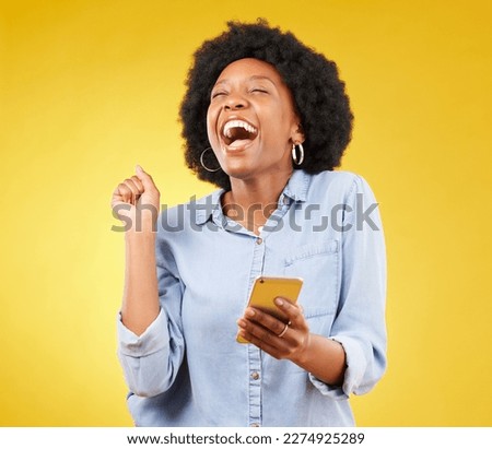 Happy, excited and phone with black woman in studio for text message, notification and social media news. Deal, winner and celebration with girl on yellow background for offer, giveaway and surprise Royalty-Free Stock Photo #2274925289